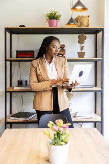 Businesswoman standing in an elegant hotel room, using a laptop to manage her business efficiently