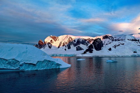 Iceberg and mountains reflected in the water at dusk, icebergs in the Southern Ocean in Antarctica