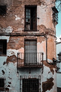 Dilapidated building with weathered balconies and shutters