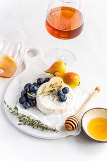Elegant cheese platter with creamy brie, ripe pears, and juicy blueberries, accompanied by a glass