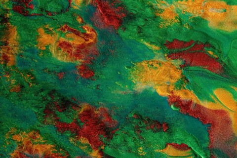 Vibrant swirls of metallic green and red paint create a textured abstract art background