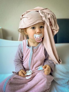 Child in pyjamas with dummy and scarf, lovingly and playfully depicted