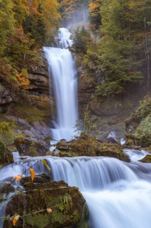 Rushing waterfall surrounded by autumnal forest and moss-covered stones, Grandhotel Giessbach, Lake