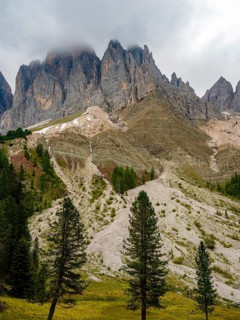 Geisler peaks rise above the rock layers into the cloudy sky, Villnöss Valley, Sass Rigais,