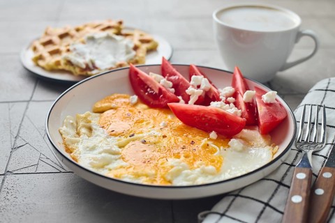 From above a delicious homemade breakfast featuring fried eggs with feta cheese and fresh tomato