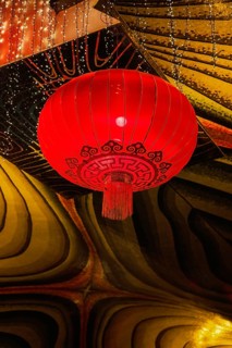 A vivid red lantern adorned with intricate patterns hangs in the festive atmosphere of a Taoist and
