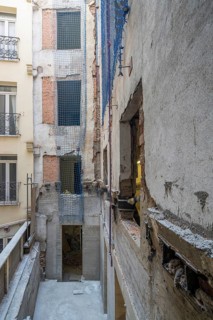 Urban building renovation site with exposed concrete and brick walls. Blue safety nets secure open