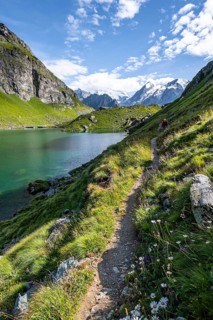 Mountaineer on a hiking trail at a mountain lake with a view of glaciated mountain peaks, Lac du