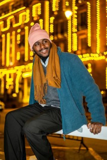 Vertical portrait of an african man sitting outdoors in a Christmas night in the city