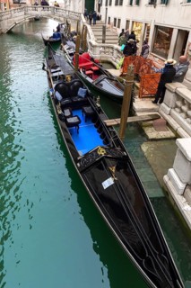 Gondoliers waiting for customers at their gondolas, Venice, Veneto, Italy