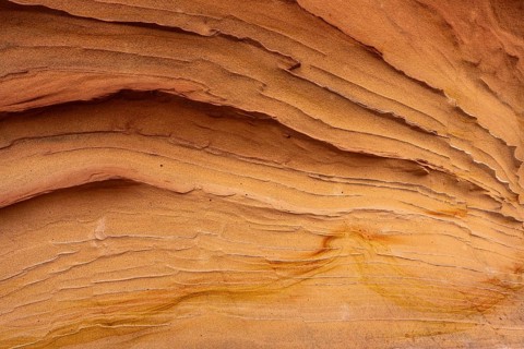 A detailed look at sandstone abstract textures, showcasing smooth, layered lines in warm tones. The