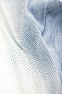 Fragment of blue and white linen tissue. Side view, textile blurred background and texture. Water
