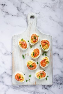 Boiled eggs stuffed with yolk and seasoned with mayonnaise, stuffed eggs with shrimp, on a white