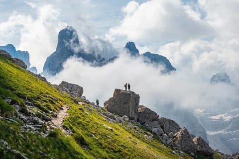 Alpine panorama, mountaineers on a large rock, fog and Torre Di Brentai and Cima Tosa, rocky