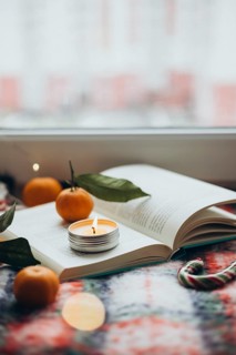 Warm and inviting Christmas scene featuring a lit candle placed on an open book, surrounded by