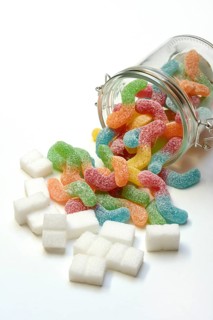 Lots of colorful jelly sweets in glass containers and sugar cubes, sugar consumption