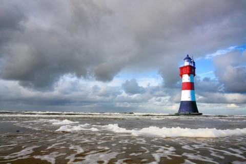 The lighthouse Roter Sand in front of blue sky with cumulus clouds and surf waves, Weser estuary,