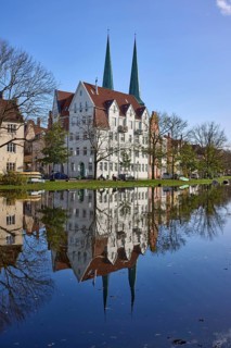 Historic house, towers of Lübeck Cathedral, trees, reflections on the surface of the water,