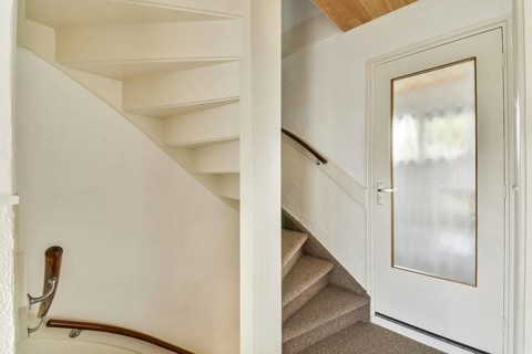 A minimalist indoor staircase with a modern design featuring light colored walls, a wooden