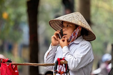 Woman with traditional straw hat making a phone call outdoors, A woman talking on the phone in the