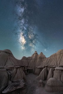 A breathtaking night sky filled with the Milky Way stretches above the unique, weathered rock