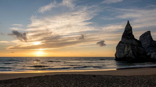 A stunning sunset over a tranquil ocean with majestic rock formations on the shoreline of bear