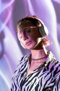 A young, trendy woman wearing headphones enjoys music. Her stylish zebra-print shirt and modern