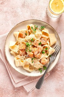 Tagliatelli pasta, with salmon slices and herbs, on a decorative plate, homemade, no people