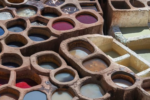 Aerial view of traditional leather tanning pits filled with vibrant dye baths in warm sunlight in