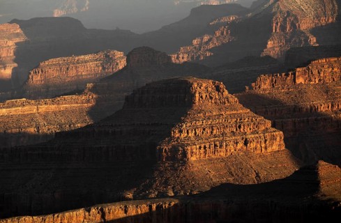 The Grand Canyon's rugged terrain is bathed in warm hues during sunset. This iconic USA landmark
