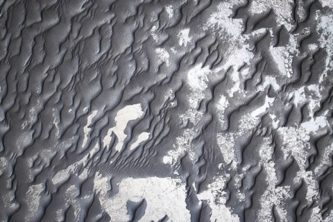 From above intricate patterns of black sand adorned with subtle white shades, creating a visually