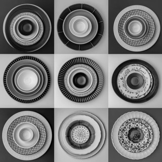 Monochrome plates and bowls with diverse geometric patterns form a striking arrangement in a grid.