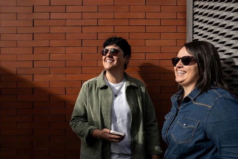 A happy curvy lesbian couple enjoying a sunny day outdoors. They are smiling, wearing casual