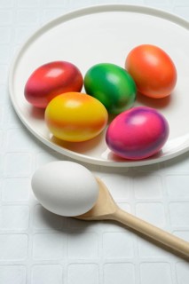 Coloured eggs on a plate and uncoloured eggs on a spoon, Easter celebration