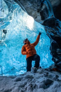 A man in an orange jacket in a glacier cave in Iceland in winter