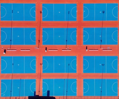 From above, this image captures a series of neatly arranged netball courts in the heart of
