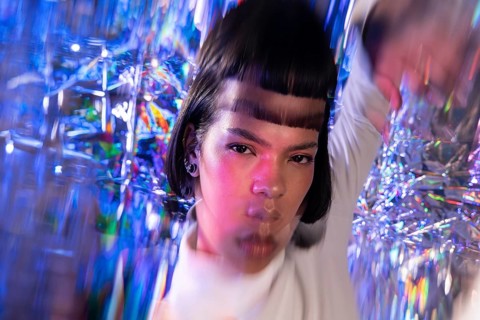 A futuristic Latin woman is immersed in the metaverse. Surrounded by prismatic lights and digital