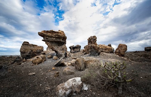 Eroded rock formations in volcanic landscape with dramatic cloudy skies, Ciudad Estratificada or
