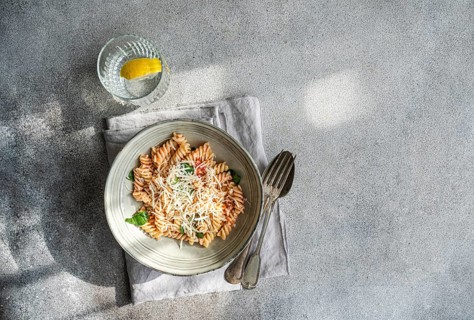 A delectable plate of cavatappi pasta topped with fresh basil, cheese and spicy tomato sauce