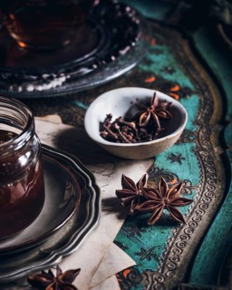 A cozy arrangement featuring a cup of tea infused with anise, presented on an ornate table. The