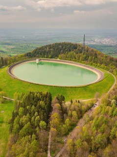 Upper reservoir, view of a water reservoir surrounded by green landscape and forest, Glems