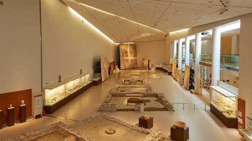 Long room in the museum with archaeological artifacts and well-lit display cases, Patras