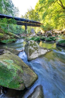The Irrel Waterfalls, rapids in the lower reaches of the Prüm, covered wooden bridge for hikers,