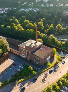 Aerial view of an industrial building on a street in a town with many trees and daylight, Calw,