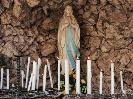 Statue of Mary in a stone sanctuary surrounded by burning candles, Franconian Switzerland