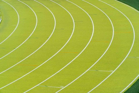 A vibrant aerial shot of a freshly marked bright green running track at an outdoor athletics