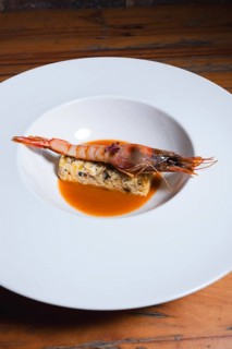 Juicy grilled prawn served on a bed of herb-seasoned egg terrine, accompanied by a flavorful orange