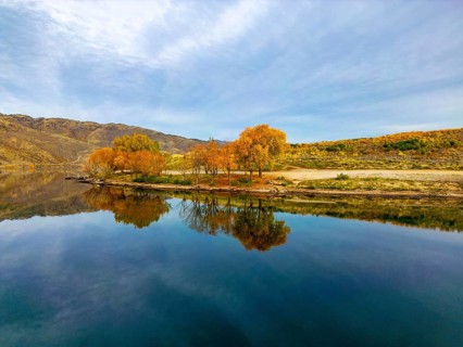 Aerial view capturing the serene beauty of Queenstown in autumn. The lake reflects the vibrant