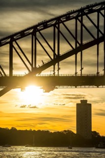 Tourists climbing Sydney harbour bridge at sunset, Sydney, New South Wales, Australia