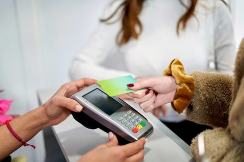 A client at a beauty salon completes a payment transaction by tapping a card on a device. The